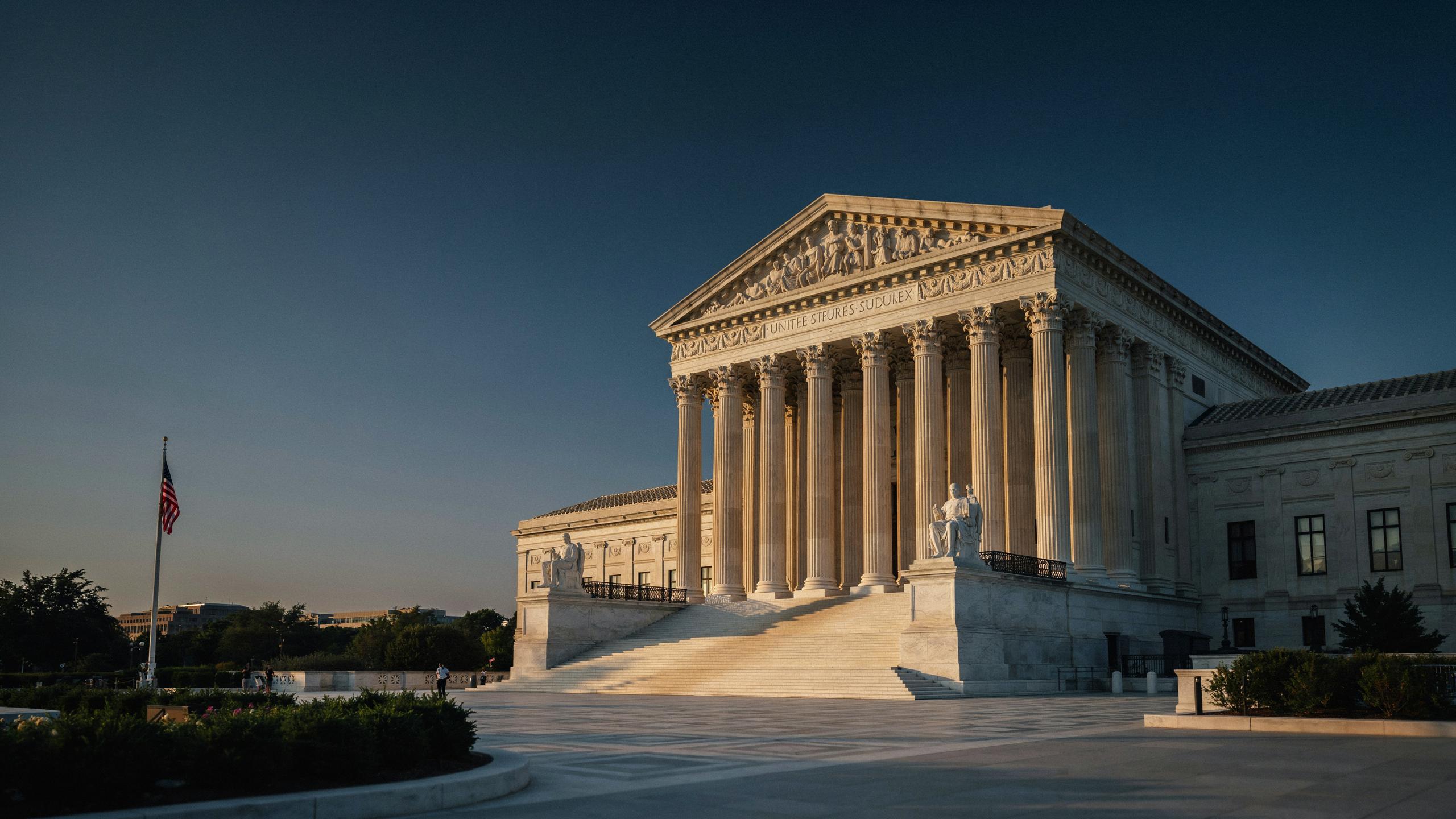 United States Supreme Court building at dusk, white marble columns in warm golden light